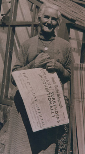 Mrs. Mc Causland holding a copy of the Irish Daily Telegraph, carrying headline, 'Germany surrenders unconditionally', May 1945. From Ballymoney Museum Collection.